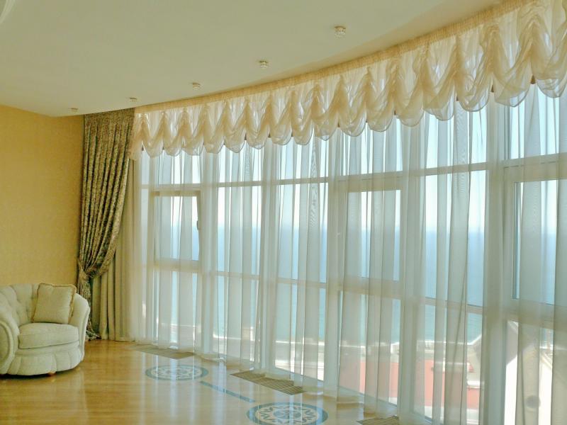 Panoramic window in the living room with French curtains