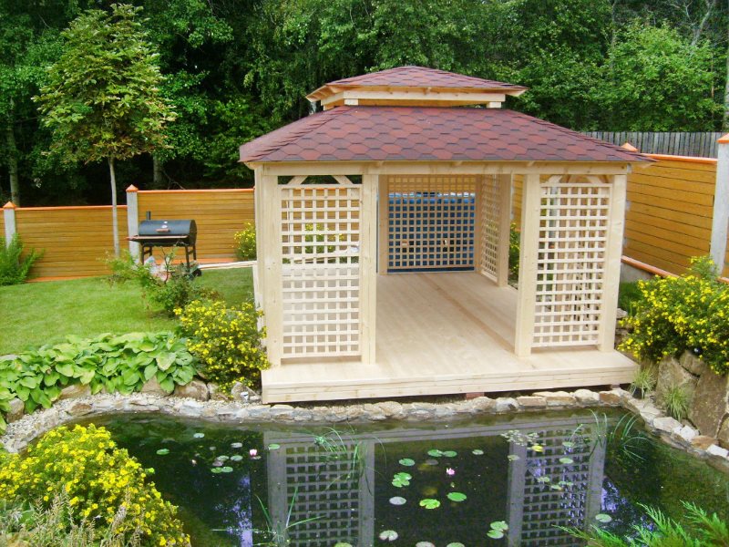 Wooden arbor on the shore of the garden pond