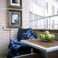 A table with an armchair on the balcony of a studio apartment