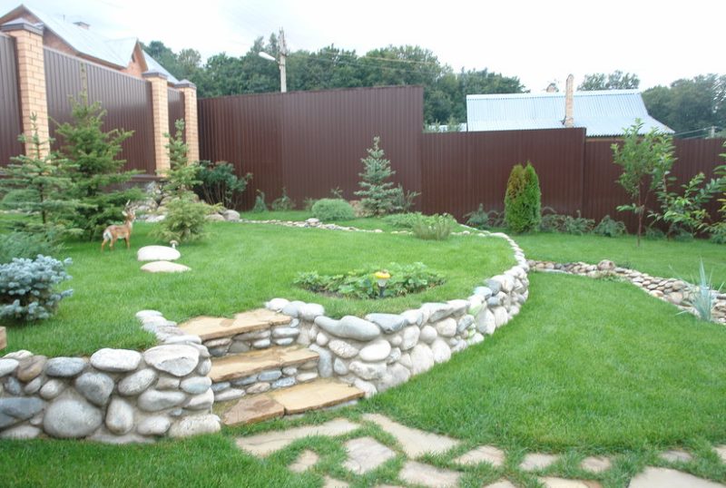 Low retaining wall made of rubble stone in a summer cottage