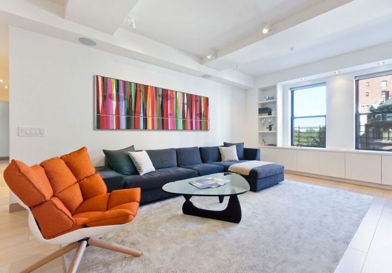 Design of a white living room with an orange armchair in the interior