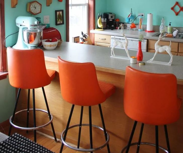 Orange chairs along the bar counter in the kitchen
