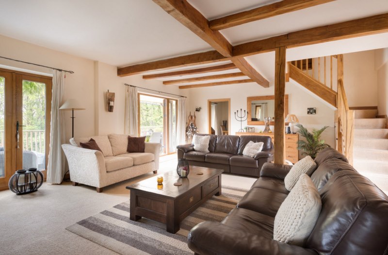 Travi in ​​legno sul soffitto del soggiorno con un divano marrone