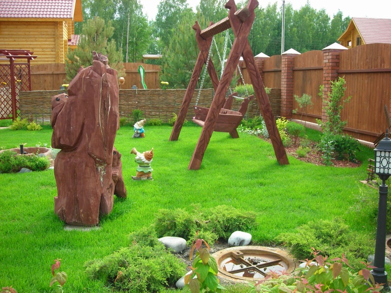 Balançoire en bois sur la pelouse verte d'un jardin privé