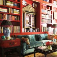Red shelves for books in the living room above the sofa