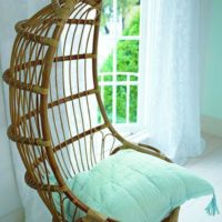 Suspended wicker chair with a mint pillow