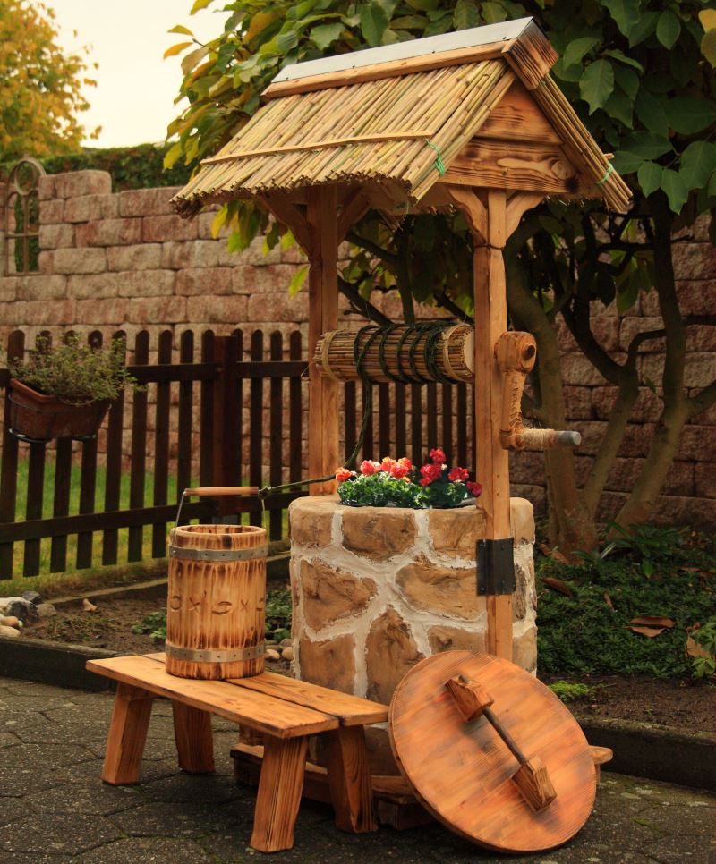 Petite forme architecturale pour le jardin sous la forme d'un puits décoratif en pierre et en bois