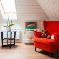 Red armchair in a white nursery with sloping walls