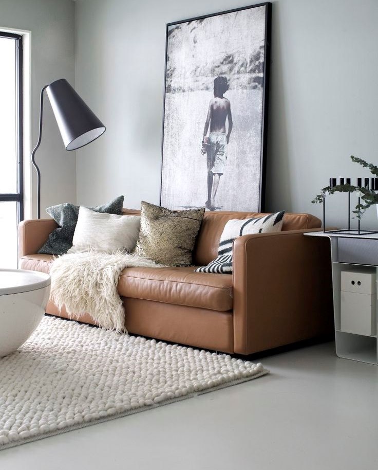 Interiore del salone con divano marrone sul pavimento grigio chiaro.