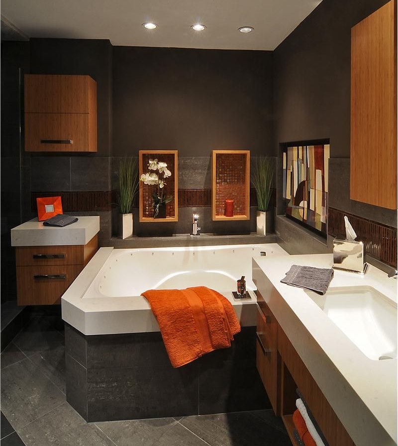 Orange towel on the edge of the bath in a dark brown room