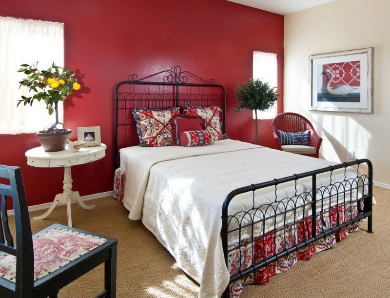 La combinazione di biancheria da letto bianca con un muro rosso nella camera da letto