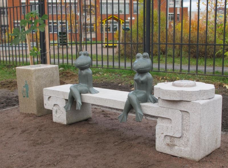 Figure ukrašenih žaba na ukrasnoj klupi