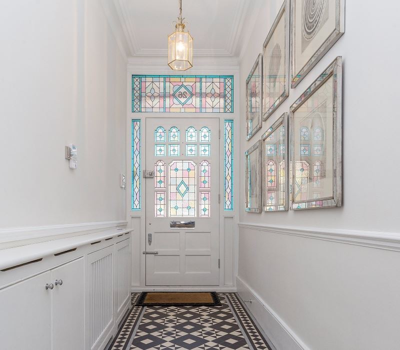 White door with stained glass windows in a narrow corridor