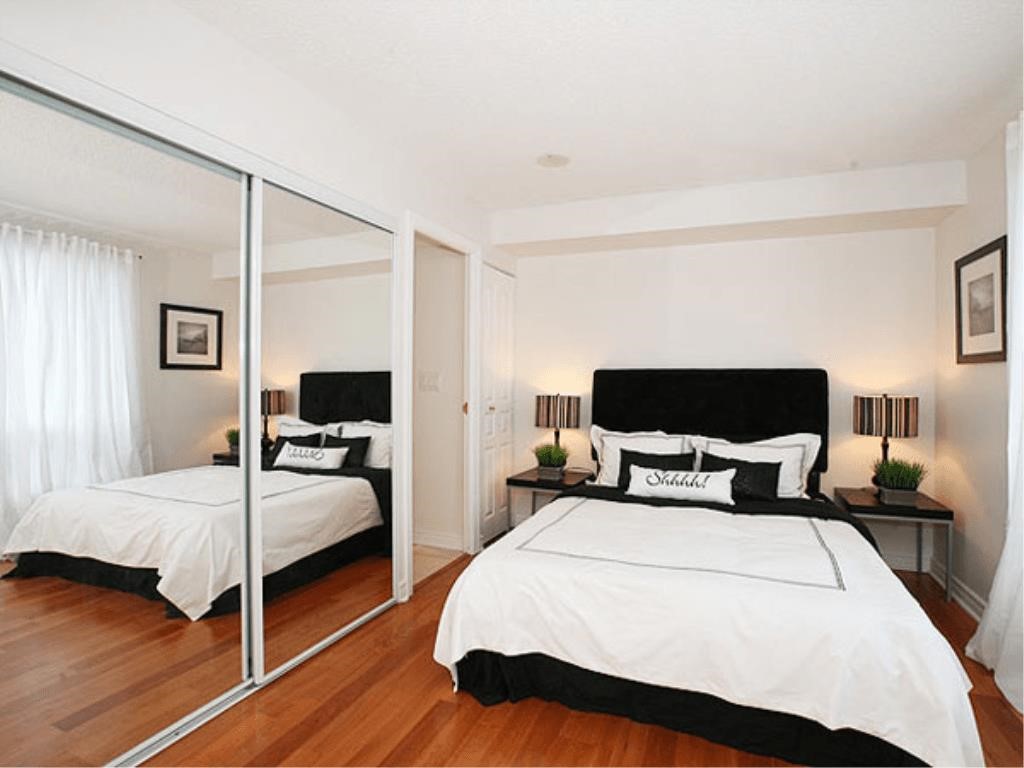 Large mirrors on the wall of a narrow bedroom