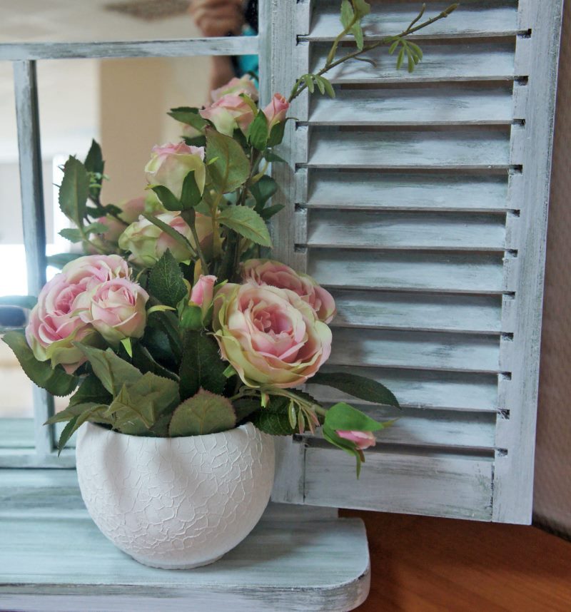 Pot de roses en fleurs sur un rebord de fenêtre en bois