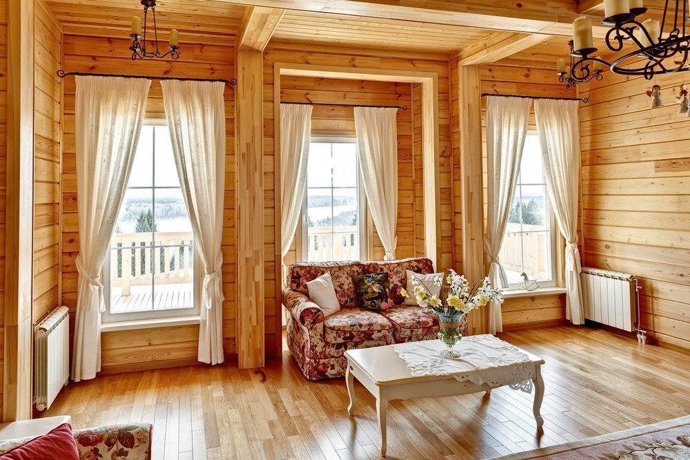 Trois fenêtres dans le salon d'une maison en bois