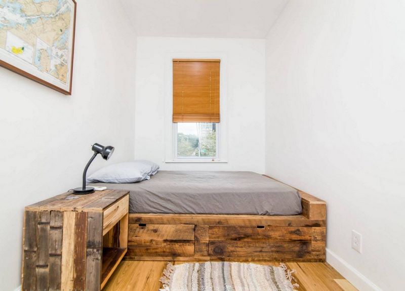 Bed on a wooden podium in a narrow bedroom