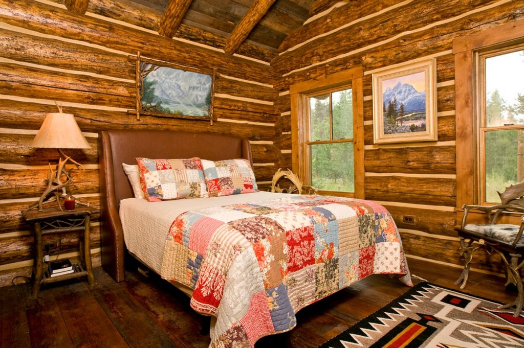 Variegated bedspread from fabric flaps on a bed in a log house