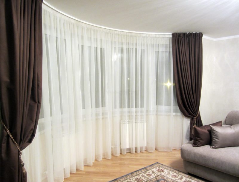 Black curtains with white tulle on the window of the hall in the style of minimalism.