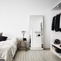 A large mirror on the floor of a bright bedroom