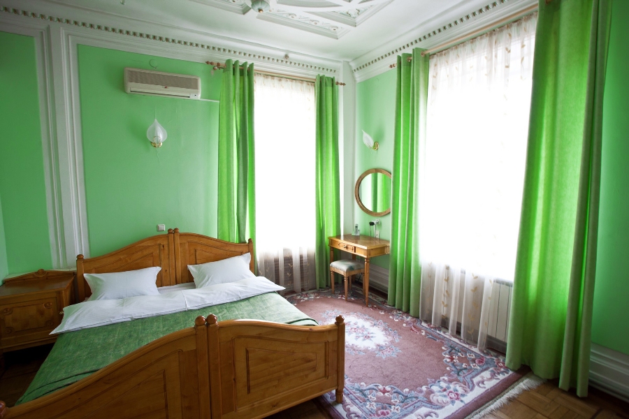 Pareti e tende verdi all'interno di una camera da letto per adulti