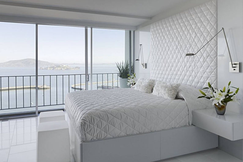 Letto bianco nella camera da letto con finestra panoramica