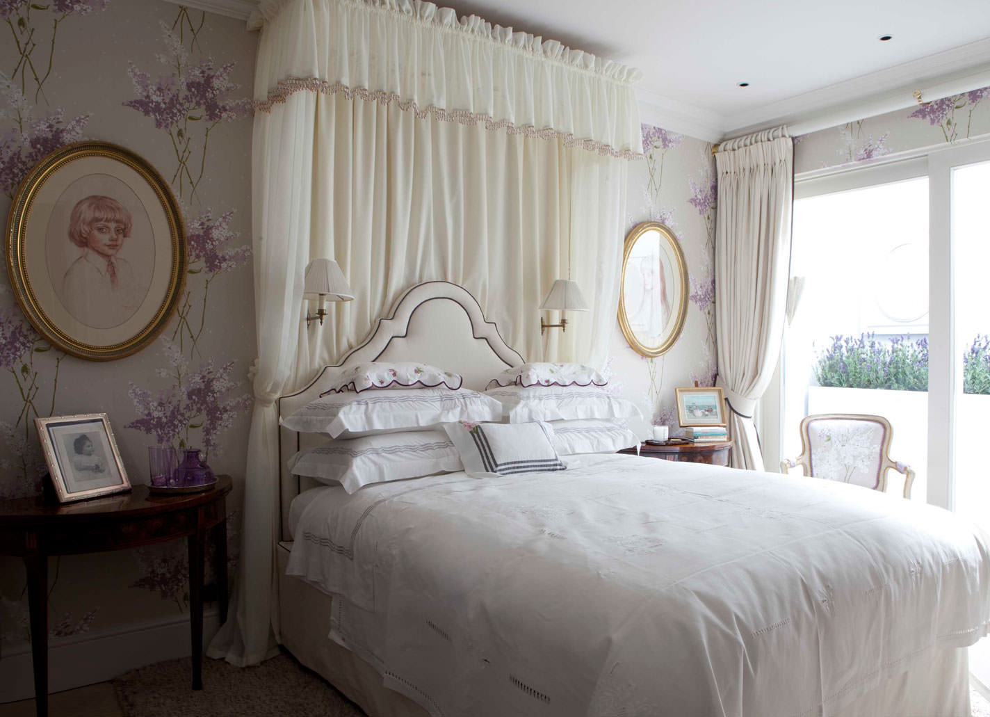 White canopy in the bedroom with portraits on the wall