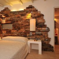 Décoration avec mur de pierre artificielle au dessus du lit