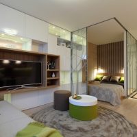 Bed behind a glass partition in a studio apartment