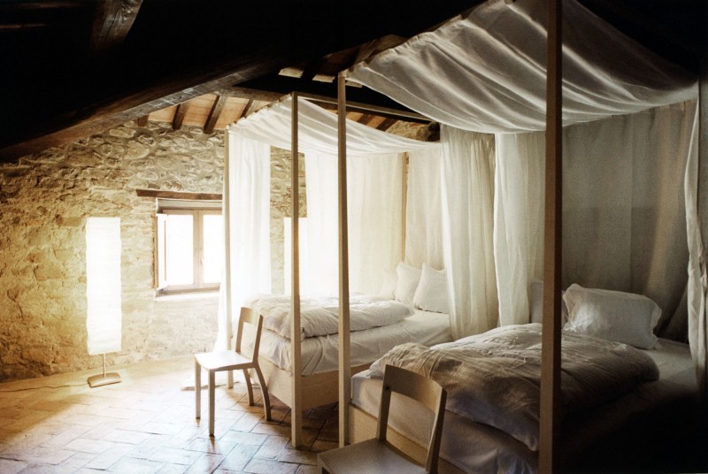 Simple four-poster beds in stone-walled room