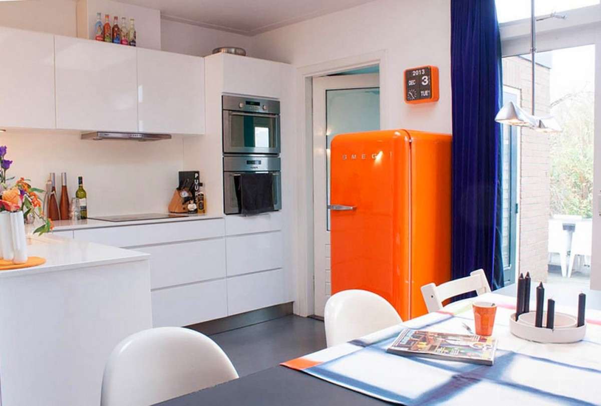Réfrigérateur orange dans la cuisine avec un ensemble blanc