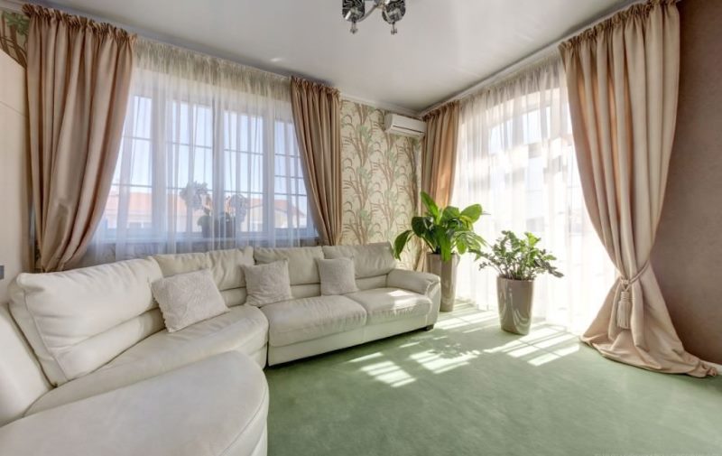 Beige curtains in the living room with corner sofa