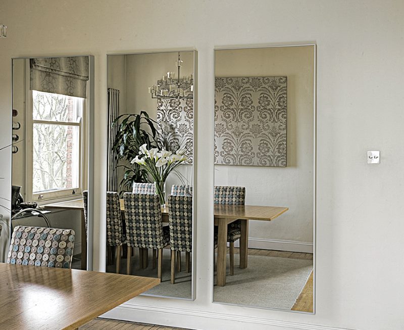 Tre specchi senza cornici sul muro della cucina-sala da pranzo