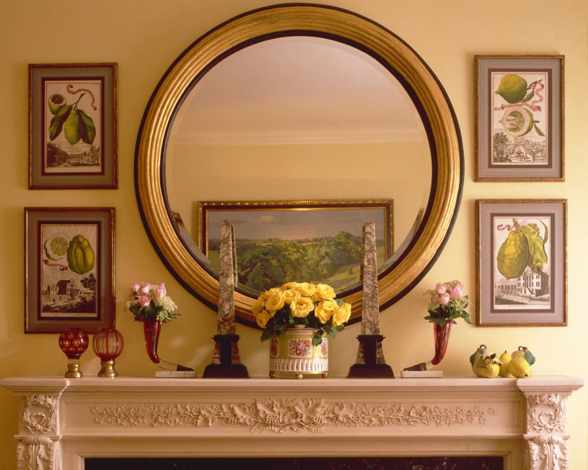 Round mirror in a gold frame over the fireplace