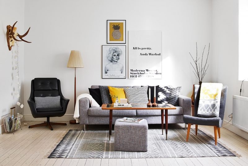 Black armchair next to a gray sofa in a white living room