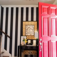 Striped wallpaper in the hallway with a pink door