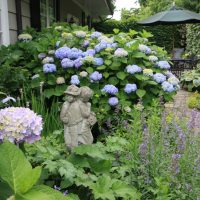 Garden sculpture against a background of hydrangea with lilac flowers