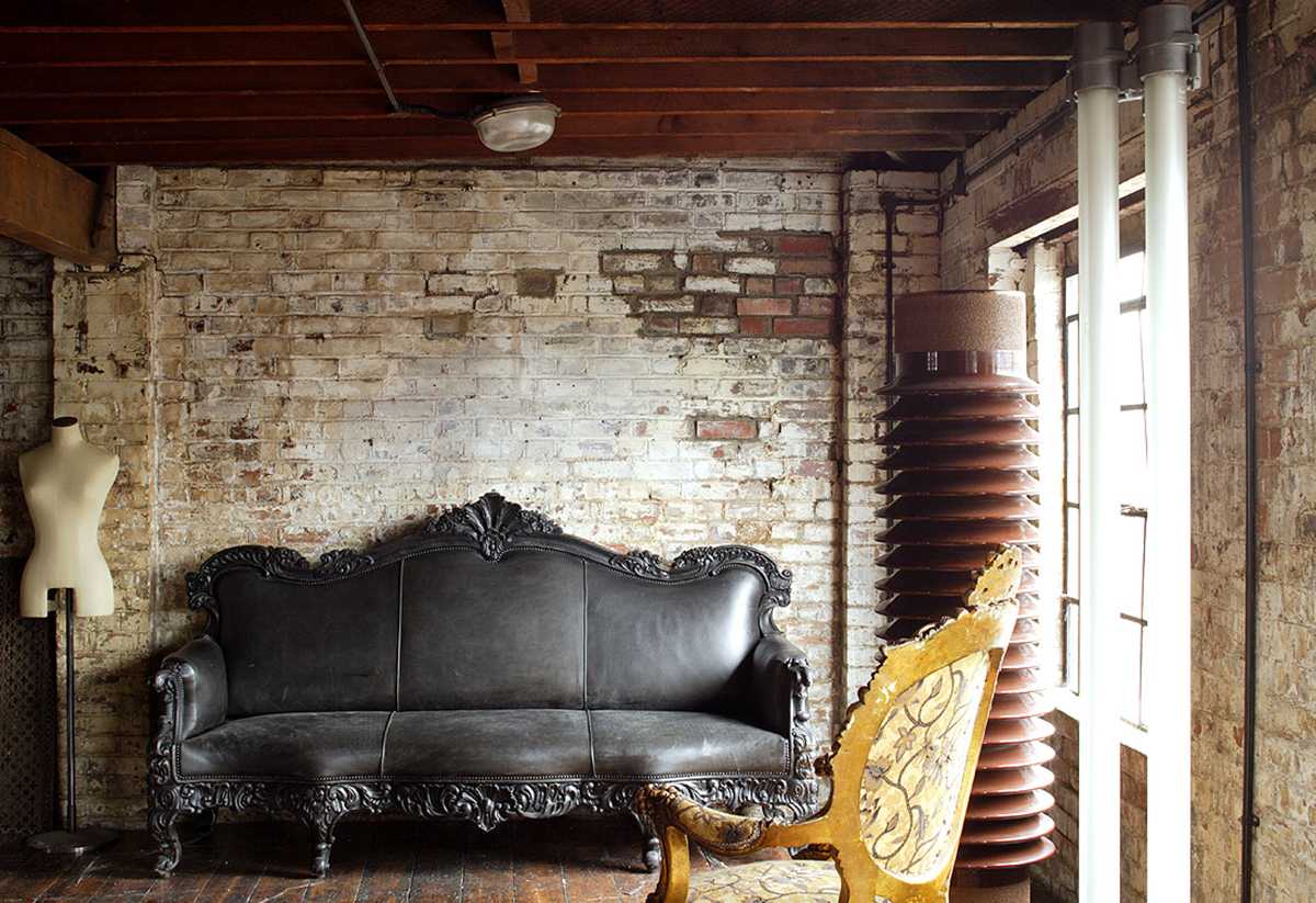 Black sofa near rough brick wall