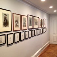 A collection of paintings on the wall of a narrow corridor