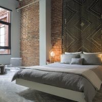 Carpet over the head of the bed in the bedroom with a brick wall