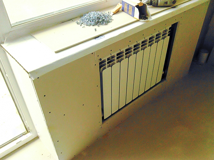 Installazione di fogli per cartongesso su una scatola decorativa del sistema di riscaldamento