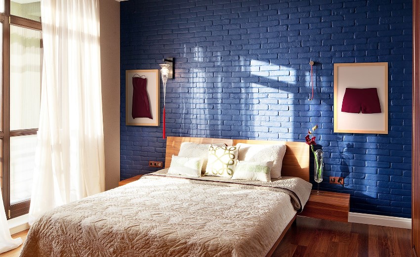 Lit double dans une chambre avec un mur de briques bleues
