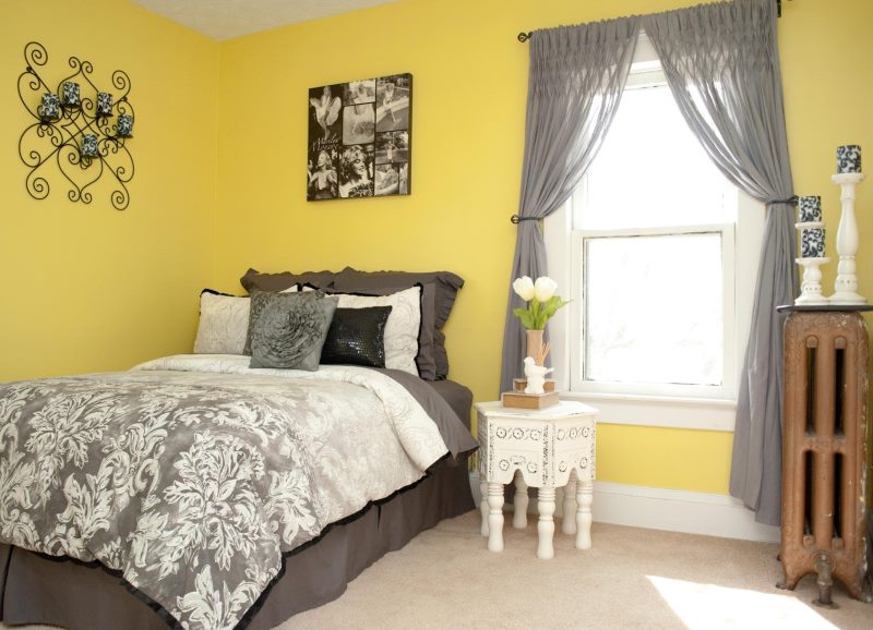 Tende grigie traslucide nella camera da letto con pareti gialle